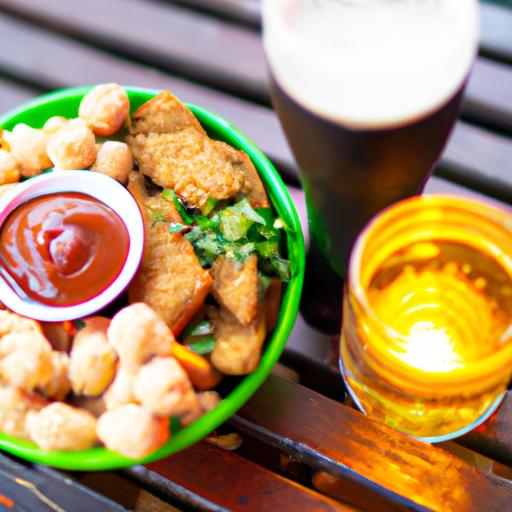 Một đĩa đồ ăn ngon và một cốc bia lạnh đặt trên bàn gỗ tại quán cafe xem bóng đá.